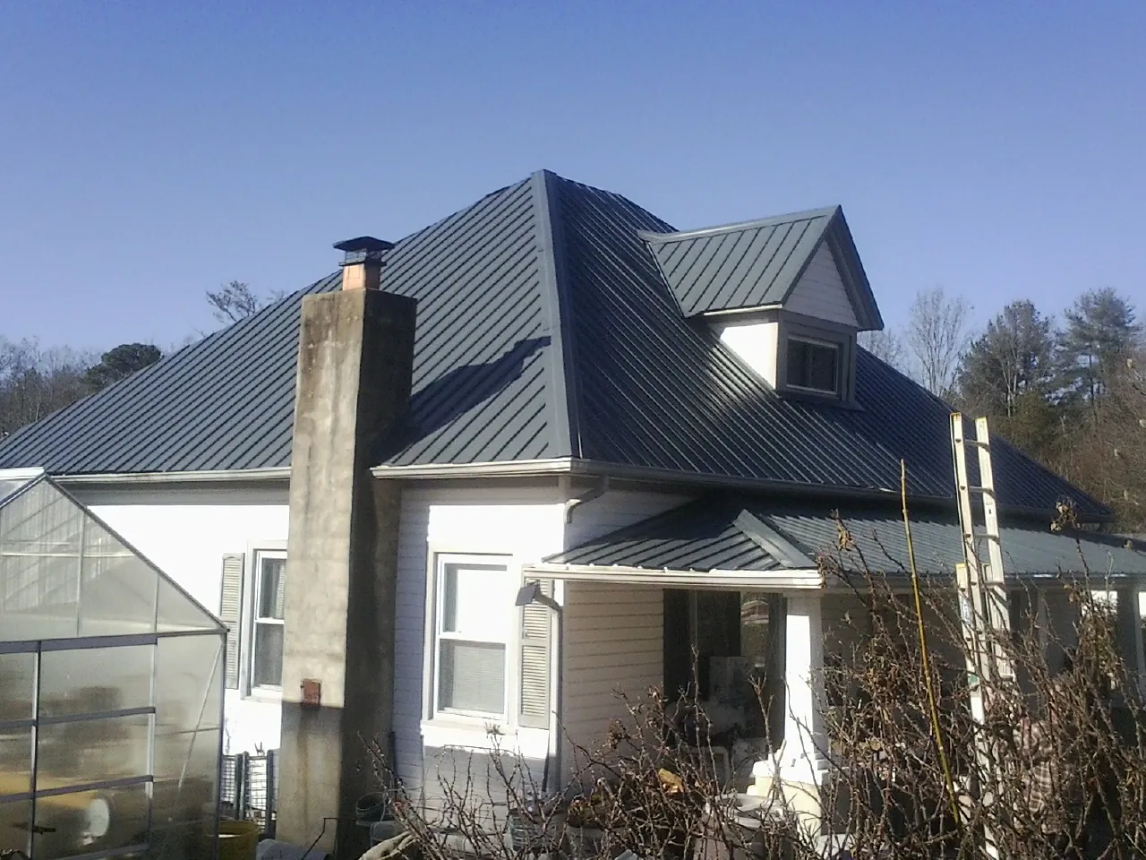 Dark blue standing seam metal roof on a white farmhouse with dormer — Slate & Tile Roof Repair by Roofing Brothers in Smoaks
