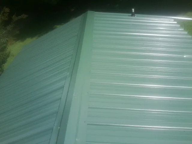 New green metal panels meeting at the ridge of a roof — Flat Roof Repair work by our crew in Smoaks