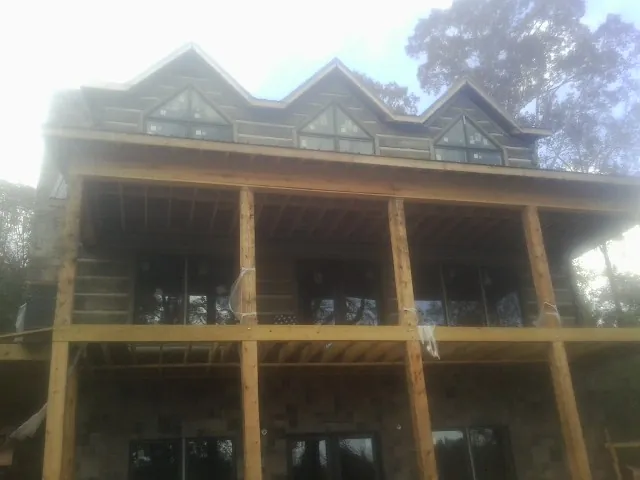 Dormers and porch framing on a large log home under construction — Roof Coating work by our crew in Smoaks
