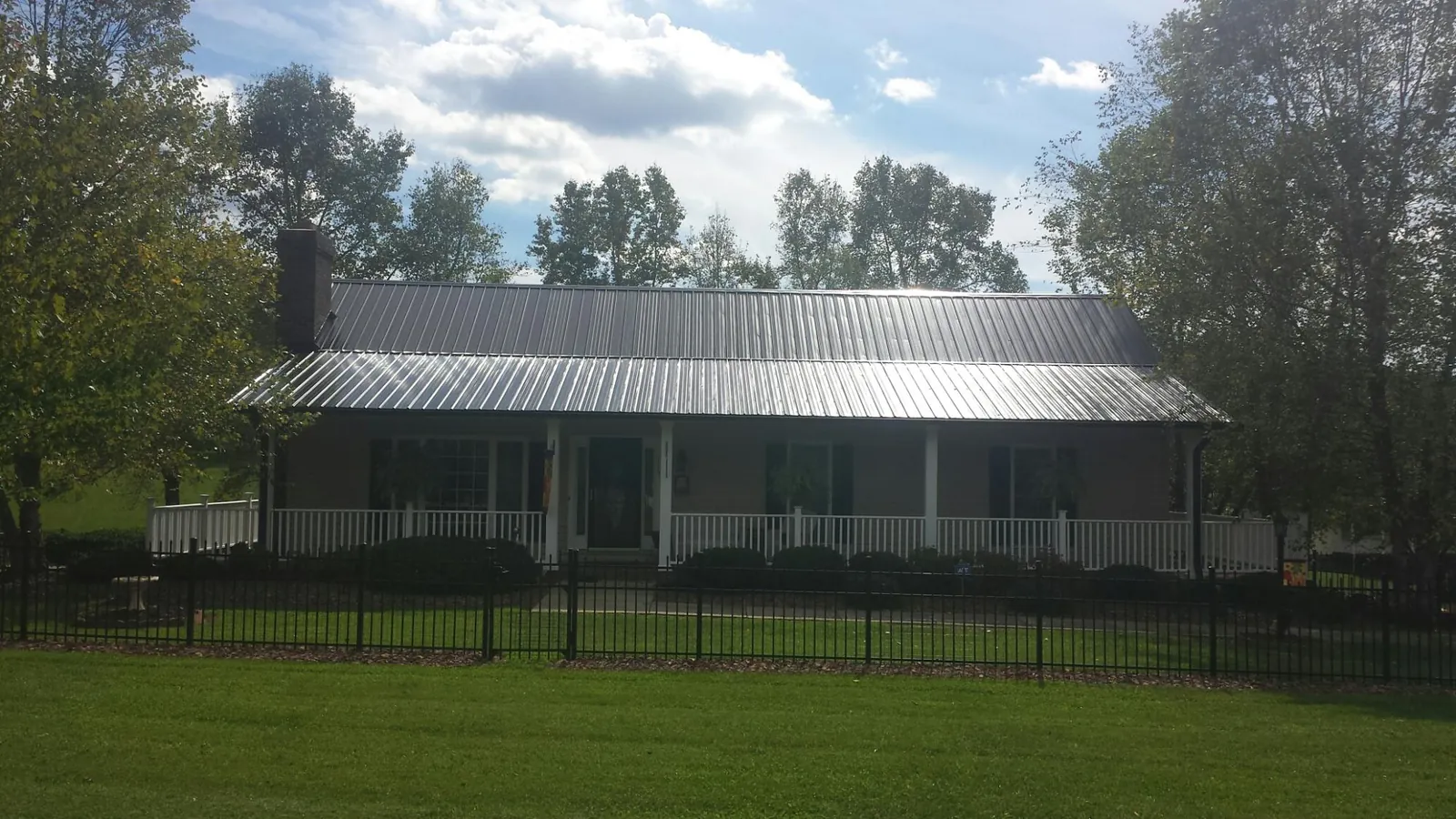 Gray metal roof on a brick ranch with a full width front porch — Gutter Guard Installation work by our crew in Smoaks