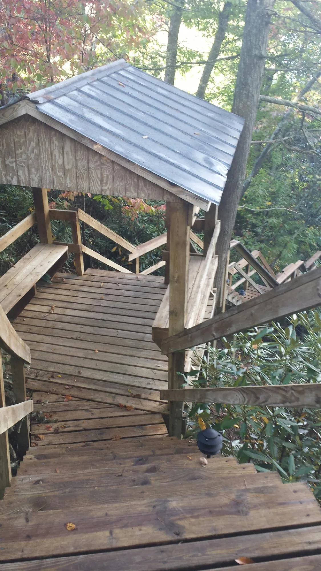Metal roofed shelter over wooden steps on a wooded walkway — Skylight Repair & Installation work by our crew in Smoaks