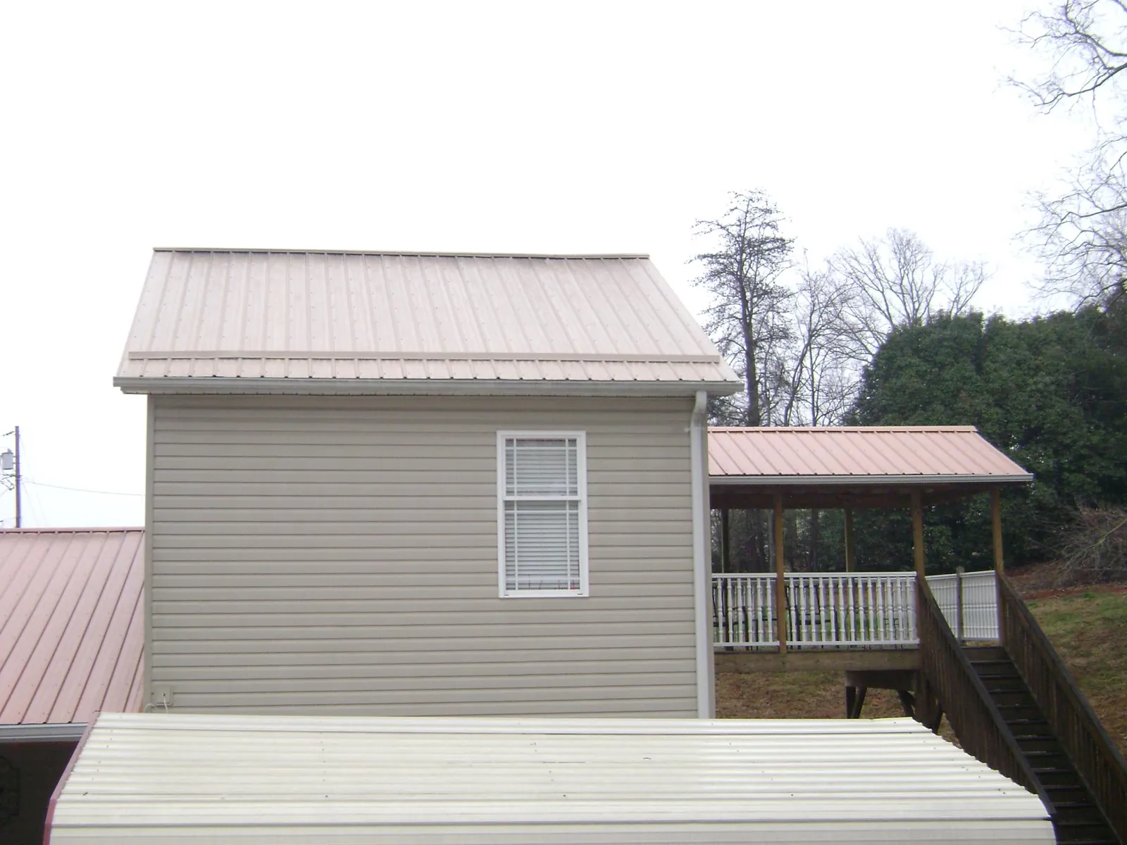 Tan metal roofs on a two story addition and attached porch, from a Roof Replacement job in Smoaks