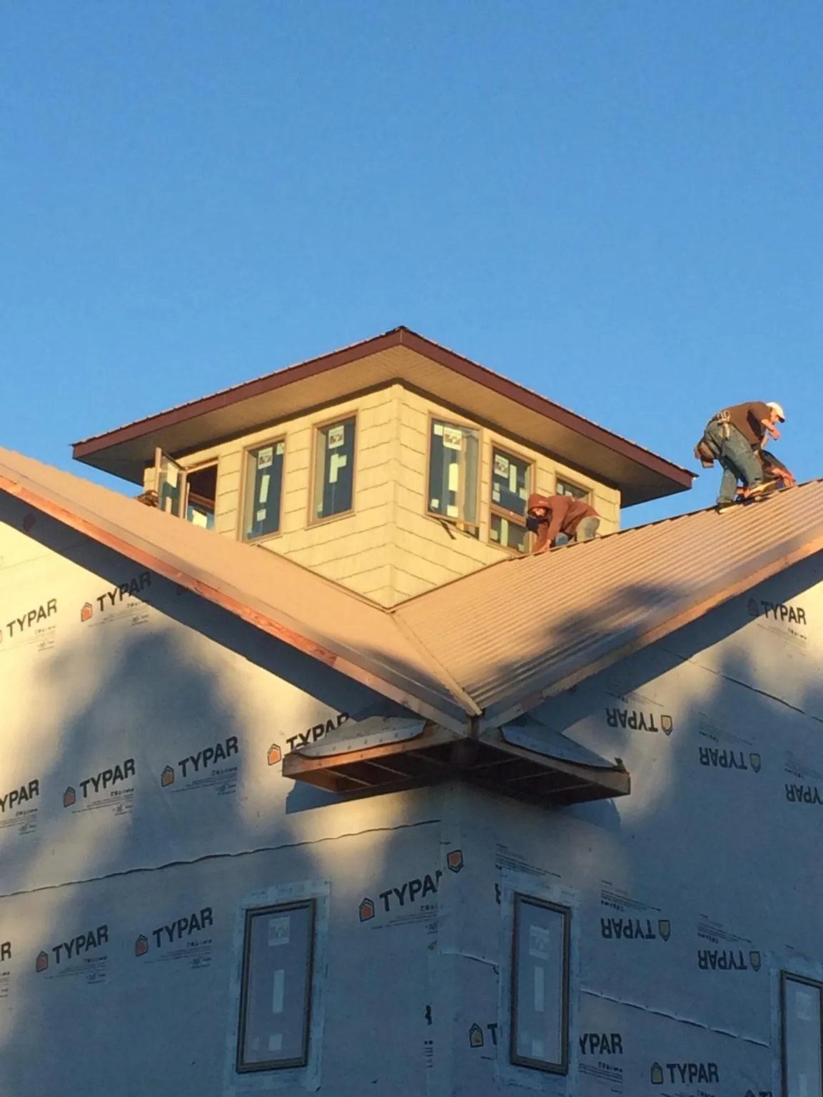 Roofers working around a rooftop cupola on a new metal roof at sunset — Roof Waterproofing in Smoaks by Roofing Brothers